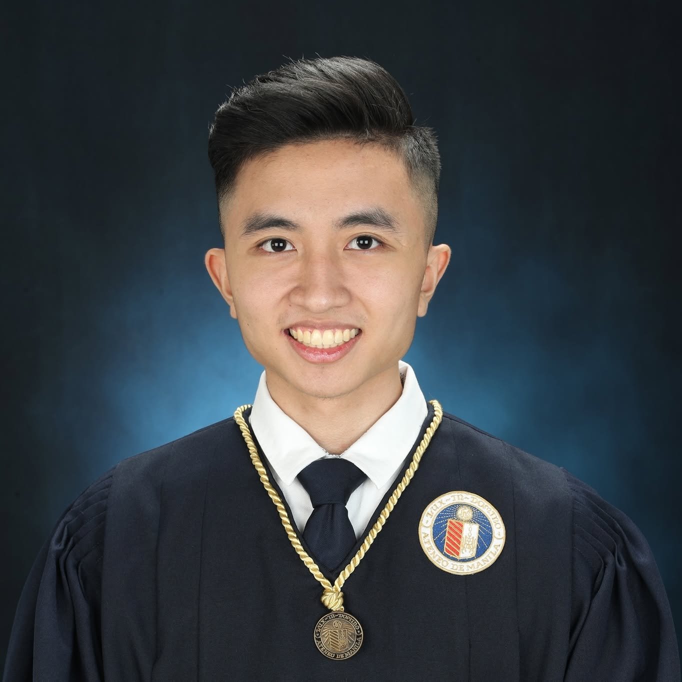 Teacher Yobhel, smiling, in a graduation gown.